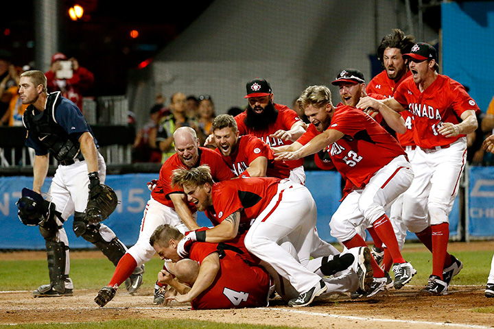 Team Canada players mob Peter Orr after he scored the game-winning run against the United States in the 10th inning of the gold medal baseball game at the Pan Am Games, Sunday, July 19, 2015, in Ajax, Ontario. 