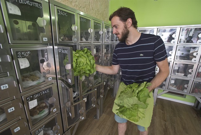 In this July 2, 2015 photo, delivery man Michael Luminau puts greens in automat boxes in Paris, France. Joseph Petit employs no staff at his two Paris stores. Both called Au Bout du Champ - "at the end of the field" - the small spaces are stacked with metal lockers containing just-picked strawberries, hours-old eggs, and neat bunches of carrots or spring onions, depending on the season. Customers simply choose the box that contains the food they want to buy, then pay at a console to open the door.