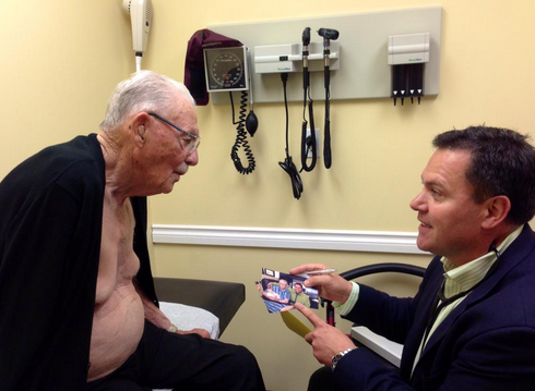 Doctor and his 100-year-old patient look at photo taken one year after the operation.