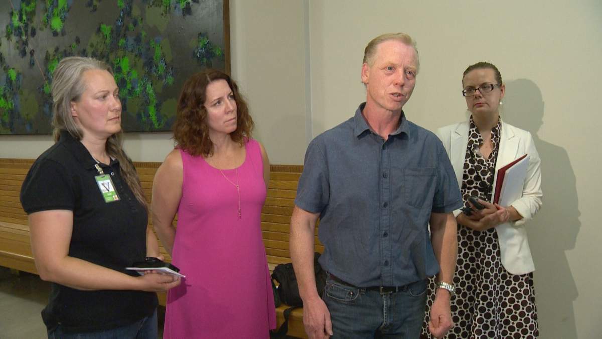 David Head (3rd from right) speaks to reporters at the Saskatchewan legislature Thursday, alongside his wife (left) and NDP health critic Danielle Chartier (2nd left).