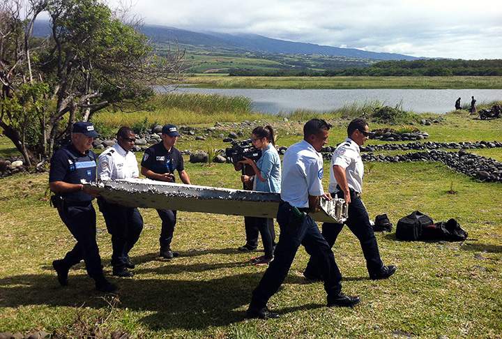 Police carry a piece of debris from an unidentified aircraft found in the coastal area of Saint-Andre de la Reunion, on July 29, 2015.