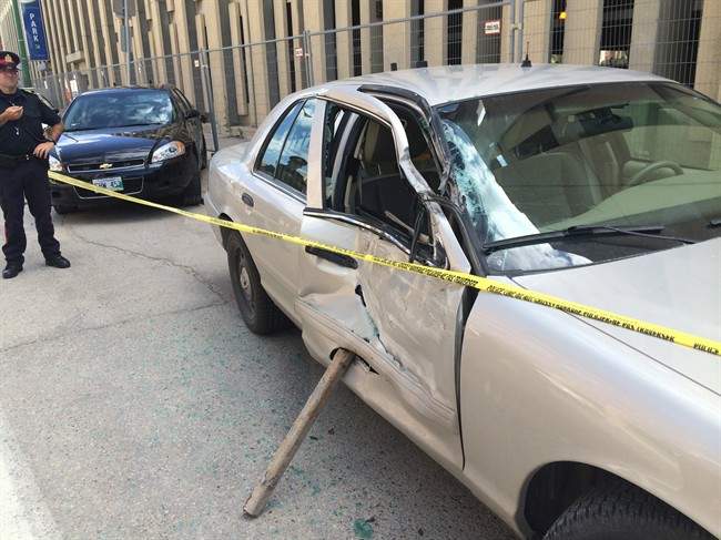 Cars are taped off after a truck driver hit five police cars outside police headquarters in Winnipeg on Monday, July 20, 2015. Police have laid a dozen charges against a 24-year-old man in the ramming of police cars in front of Winnipeg police headquarters.