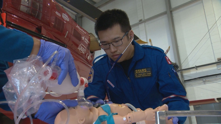 Doctor Ping Wei Chan, a pediatric transport physician, demonstrates life-saving techniques on a child-sized mannequin to promote awareness of National Drowning Prevention Week.