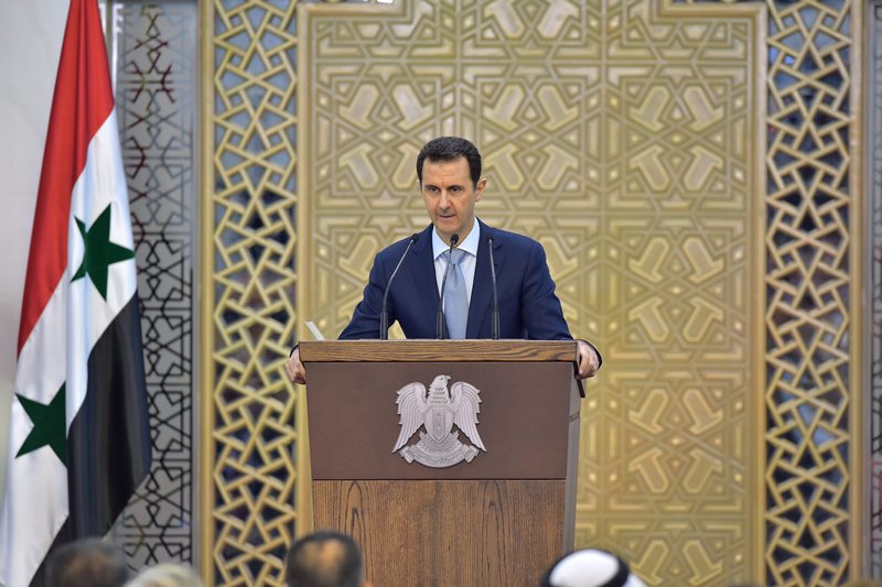 In this photo released by the Syrian official news agency SANA, Syrian President Bashar Assad delivers a speech in Damascus, Syria, Sunday, July 26, 2015. Assad says he supports any political dialogue to end his country's civil war even if its effects are limited. But he says any initiative that is not based on fighting "terrorism" will be "hollow" and "meaningless.".