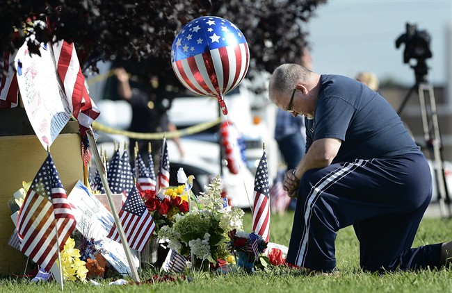 Bill Lettmkuhl kneels by a makeshift memorial near the Armed Forces Career Center on Friday, July 17, 2015, in Chattanooga, Tenn. Muhammad Youssef Abdulazeez, of Hixson, Tenn., attacked two military facilities on Thursday, in a shooting rampage that killed four Marines and a sailor. 