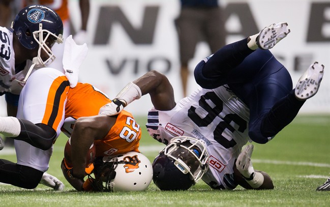 Toronto Argonauts' Brian Rolle, right, falls to the ground after tackling B.C. Lions' Alex Tillman during the first half of a CFL football game in Vancouver, B.C., on Friday July 24, 2015.