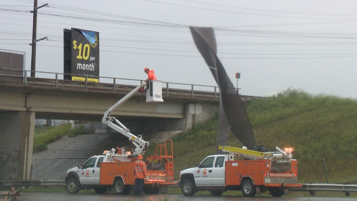 Crews work to untangle a fence that got wrapped up around a power line and dangled over Ring Road.