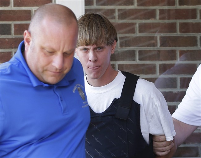 FILE - In this June 18, 2015, file photo, Charleston, S.C., shooting suspect Dylann Storm Roof, center, is escorted from the Sheby Police Department in Shelby, N.C. FBI director James Comey says Roof, the gunman in the Charleston church massacre should not have been allowed to purchase the gun used in the attack, and on July 10 attributed the problem to incomplete and inaccurate paperwork related to an arrest of Roof weeks before the shooting. (AP Photo/Chuck Burton, File).