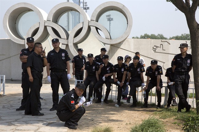 In this photo taken Sunday, May 31, 2015, Chinese security personnel rest near the Olympic rings near the Bird's Nest National Stadium in Beijing.