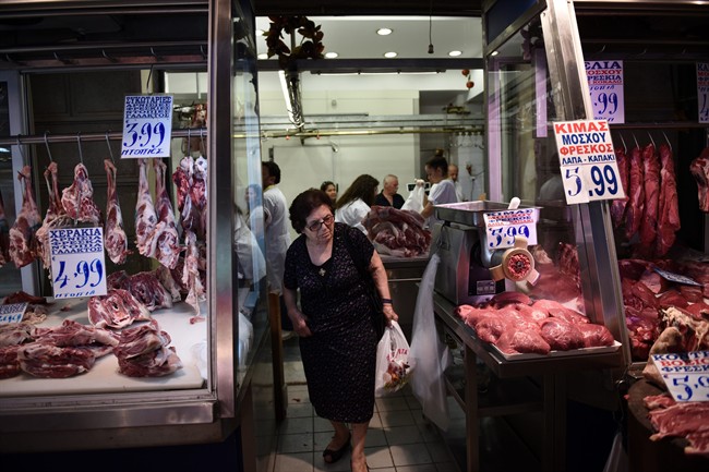 An elderly woman shops meat at Varvakios market in Athens, Saturday, July 25, 2015. 
