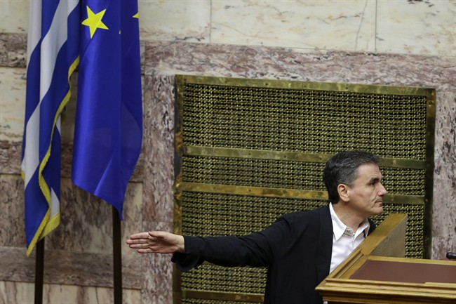 Greece's Finance Minister Euclid Tsakalotos gestures as he speaks with a lawmaker during an emergency parliament session in Athens, Wednesday, July 22, 2015.