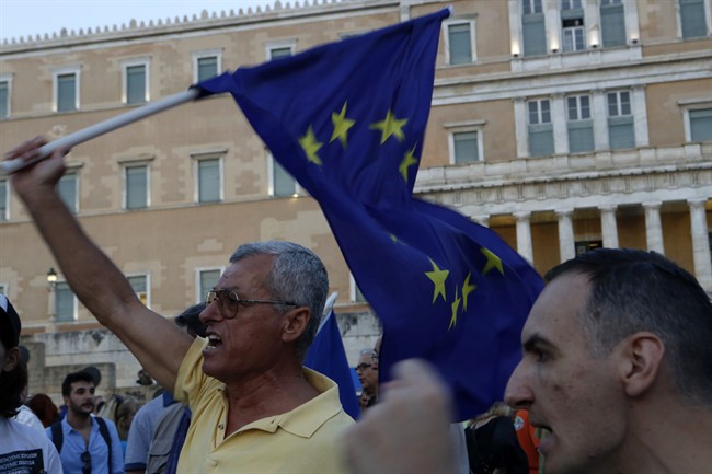 A pro-Euro demonstrator shouts slogans as he holds a European Union flag in front of the Greek Parliament.
