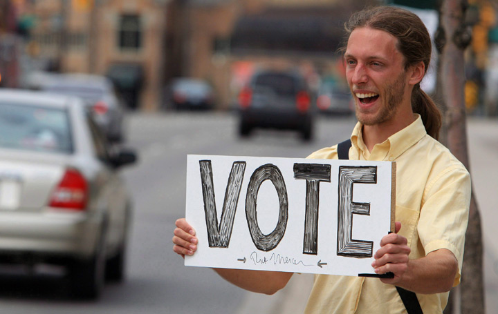Man holds a sign encouraging people to vote