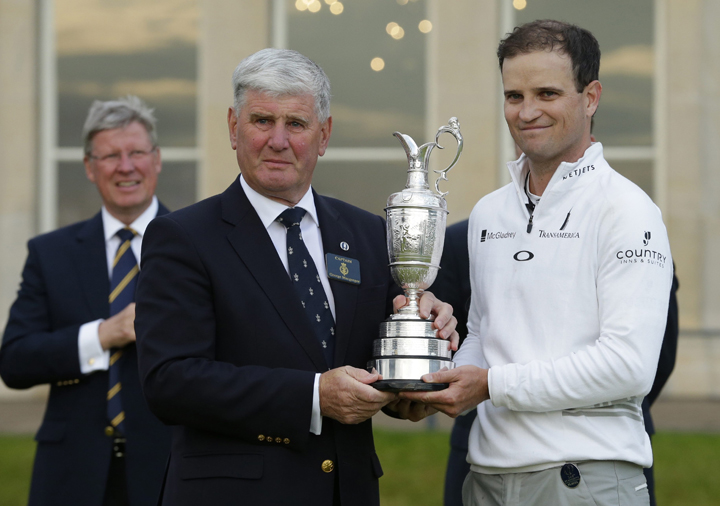 United States’ Zach Johnson, right, poses with the trophy as it is handed to him by R&A captain George Macgregor after he won a playoff after the final round at the British Open Golf Championship at the Old Course, St. Andrews, Scotland, Monday, July 20, 2015.