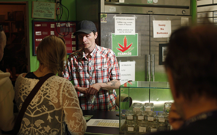 Baker and customer service employee, Shawn Saunders, sells product to a customer, at the Cannabis Buyers Club, in Victoria B.C., Thursday June 11, 2015.