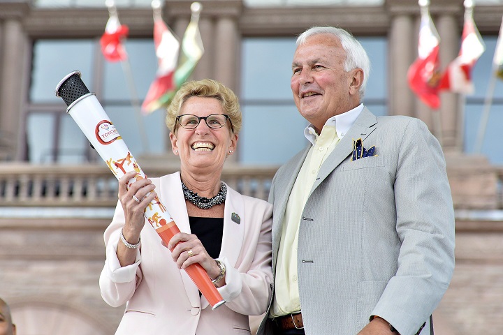 Ontario Premier Kathleen Wynne receives an honourary Pan Am Games torch from former Ontario premier David Peterson, chair of the board that is organizing the Toronto 2015 Pan Am/Parapan Am Games during a ceremony at Queen's Park in Toronto, Thursday, July 9, 2015. THE CANADIAN PRESS/Nathan Denette.