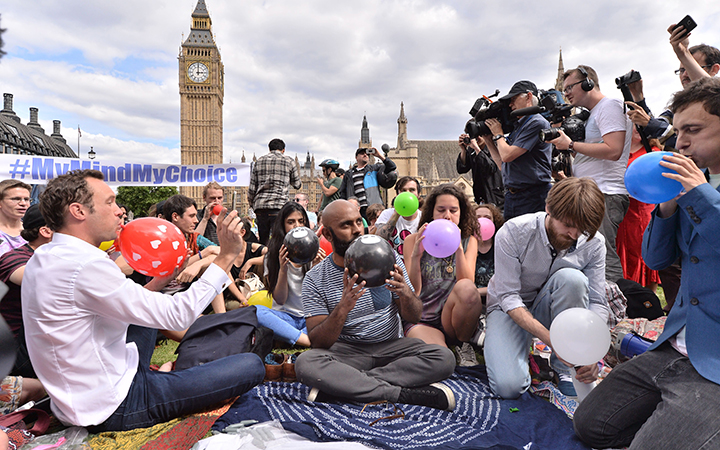 People taking part in a mass inhalation of nitrous oxide outside the Houses of Parliament in protest against the plan to crackdown on legal highs on Aug. 1, 2015 in London, England.