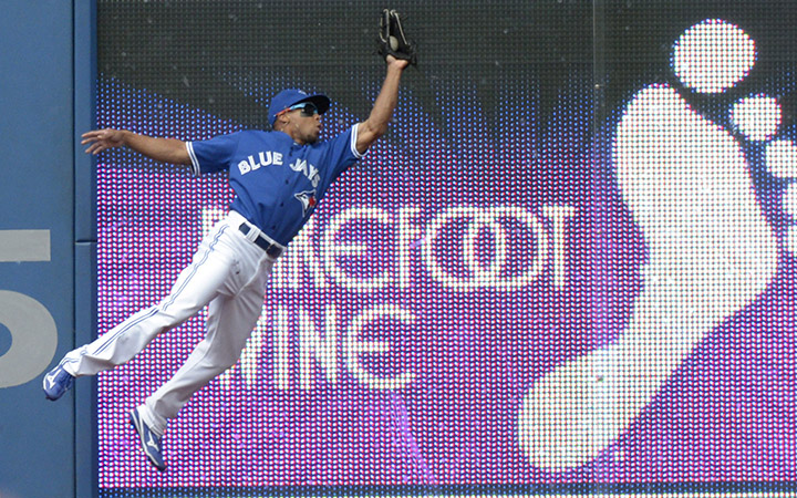 Toronto Blue Jays' Ben Revere catches a fly ball off the bat of Kansas City Royals' Kendrys Morales against the outfield wall during the fourth inning of their MLB baseball game Saturday, August 1, 2015 in Toronto.