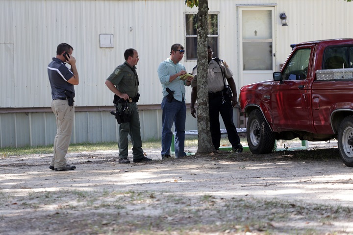 Law officers inspect a vehicle matching the description of the one used in a shooting incident outside Camp Shelby in Hattiesburg, Miss. Authorities searched Tuesday, Aug. 4, 2015, for a man who fired gunshots from a vehicle in the vicinity of soldiers at a military facility in Mississippi, although no one was reported wounded, a sheriff said. The shots were fired near a checkpoint where two soldiers were standing guard to the Camp Shelby Joint Forces Training Center, Perry County Sheriff Jimmy Dale Smith said at a news conference. (Eli Baylis/The Hattiesburg American via AP).