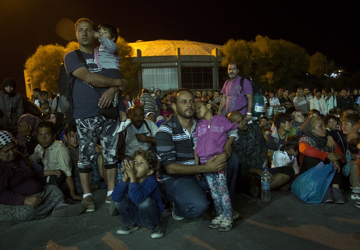 In this Sunday, Aug. 23, 2015 photo, a Syrian migrant child sleeps in the arm of her father before heading to Athens at the port town of Mytilini after crossing the Aegean from Turkey, on the southeastern Greek island of Lesbos. Some 2,500 migrants departed for Athens as Greece this year has been overwhelmed by record numbers of migrants arriving on its eastern Aegean islands, with more than 160,000 landing so far. (AP Photo/Visar Kryeziu).