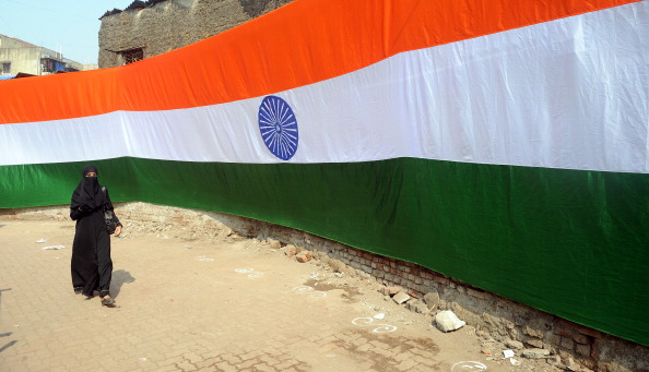 A woman walks past a portion of a over 150 feet long hand made Indian national flag hung in one of the narrow bylanes of the Dharavi slum in Mumbai on January 24, 2012. 