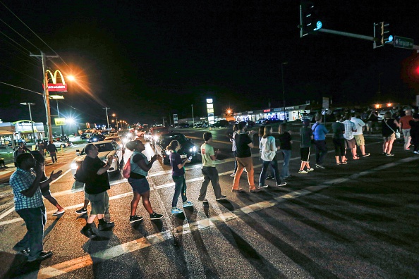 A group of protester gather along West Florissant Avenue and block the street marking the one-year anniversary of the shooting of Michael Brown, in Ferguson, Mo., on August 12, 2015. Brown was shot and killed by a Ferguson police officer on August 9, 2014. (Photo by Cem Ozdel/Anadolu Agency/Getty Images).
