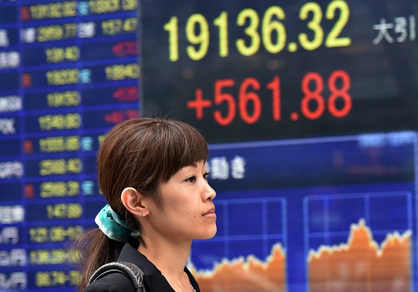 A woman passes before a share prices board in Tokyo on August 28, 2015. Japan's share prices rose 561.88 pooints to close at 19,136.32 points at the Tokyo Stock Exchange, extending gains from a day earlier after strong US data sent Wall Street flying and fuelled a global rally that saw a surge in Chinese equities. 