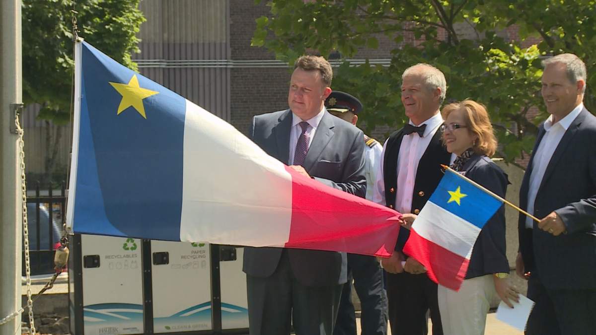 Lucien Comeau stands next to Halifax Mayor Mike Savage at a flag raising ceremony in Halifax.