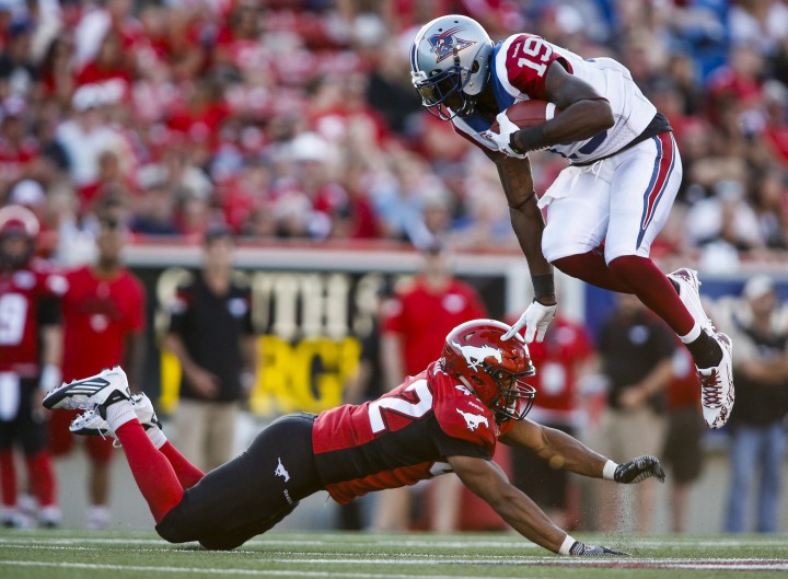 Montreal Alouettes' S.J. Green, right, leaps over Calgary Stampeders' Deron Mayo during second half CFL football action in Calgary on Saturday, August 1, 2015.