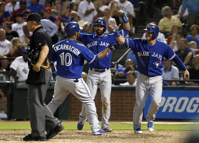 Home plate umpire Ed Hickox stands by the plate as Toronto Blue Jays' Edwin Encarnacion (10) is congratulated by Jose Bautista, center, and Josh Donaldson, right, following Encarnation's grand slam during the sixth inning of a baseball game against the Texas Rangers Wednesday, Aug. 26, 2015, in Arlington, Texas. The shot also scored Troy Tulowitzki.