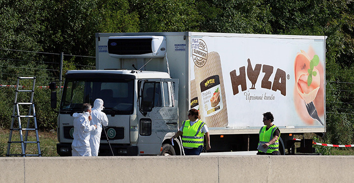 Police walk near a truck that stands on the shoulder of the highway A4 near Parndorf south of Vienna, Austria on Thursday, Aug 27, 2015. At least 20 migrants were found dead in the truck parked on the Austrian highway leading from the Hungarian border, police said. 