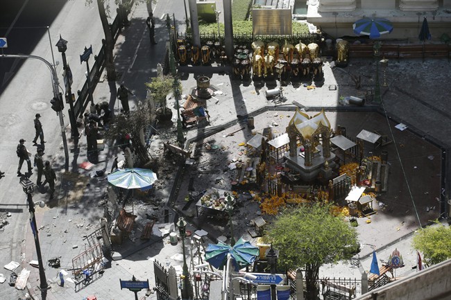 Investigators walk towards the Erawan Shrine at Rajprasong intersection in Bangkok, Thailand, Tuesday, Aug. 18, 2015, the morning after an explosion. Police combed through shattered glass and other debris Tuesday from a bomb blast in central Bangkok, trying to determine who set off the most devastating single attack in the capital's recent history. 