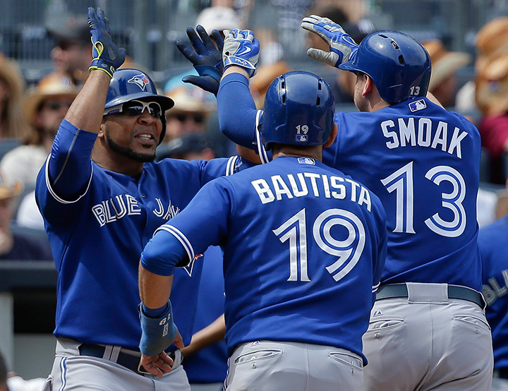 Toronto Blue Jays' Edwin Encarnacion greets Justin Smoak and Jose Bautista (19) after Smoak hit a grand slam home run against the New York Yankees during the sixth inning of a baseball game, Saturday, Aug. 8, 2015, in New York. 