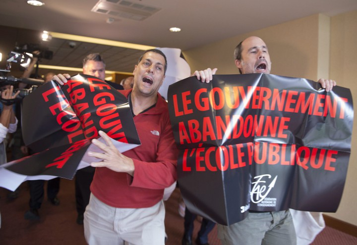 Demonstrators from a teacher's union interrupt the beginning of a Quebec Liberal government caucus meeting, Thursday, August 27, 2015.