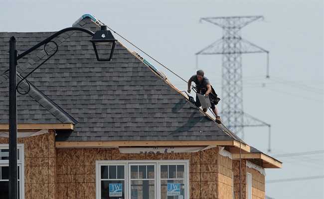 A construction worker shingles the roof of a new home in a development in Ottawa on July 6, 2015. Two Saskatchewan companies have been fined for violations of the province’s occupational health and safety regulations.