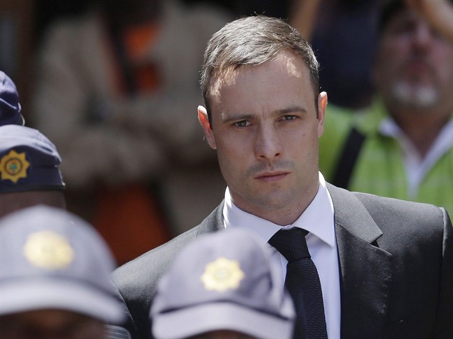Oscar Pistorius is escorted by police officers as he leaves the high court in Pretoria, South Africa on Oct. 17, 2014. Prosecutors pushing for a murder conviction against Oscar Pistorius filed papers at South Africa's Supreme Court of Appeal on Monday, four days before the Olympic runner is expected to be released from prison and moved to house arrest. THE CANADIAN PRESS/AP, Themba Hadebe.