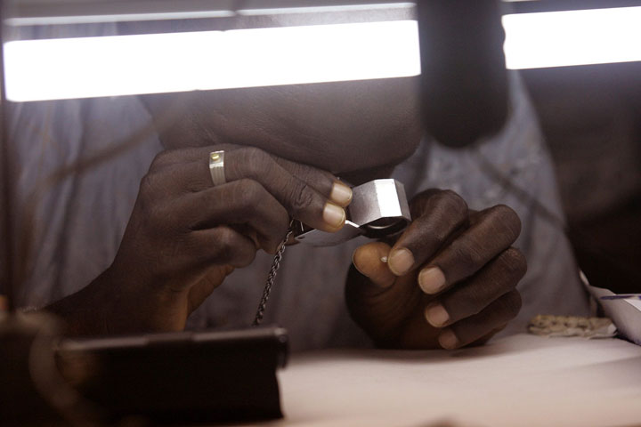 File: A diamond dealer looks at a small diamond in his office  near the town of Bo, Sierra Leone.