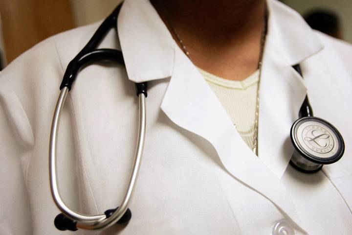 A close-up of a person in a medical coat with a stethoscope around their neck.
