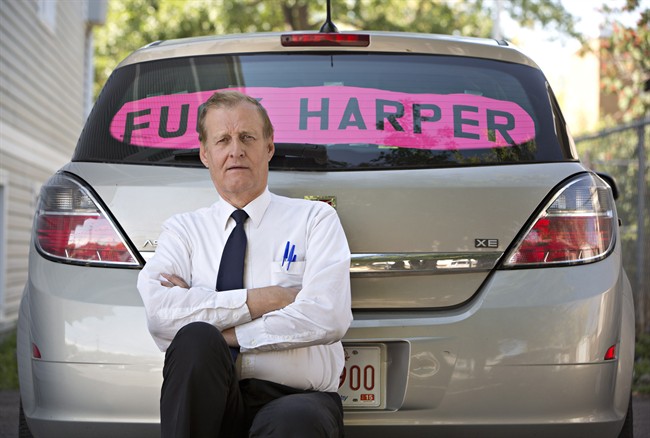 Rob Wells stands with his Steven Harper sign he put in his vehicle’s rear window in Edmonton Alta, on Wednesday Aug 19, 2015. Wells has been fined $543 by police for having the sign in his car.