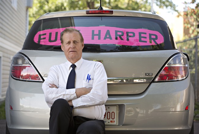 Rob Wells stands with his Steven Harper sign he put in his vehicle's rear window in Edmonton Alta, on Wednesday Aug 19, 2015. Wells has been fined $543 by police for having the sign in his car. 
