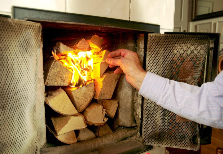 Man lights up a wood stove.