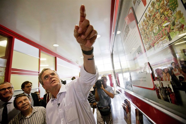 Republican presidential candidate, former Florida Gov. Jeb Bush, right, looks up at photos of celebrities who have visited The Varsity as he arrives at the restaurant for a campaign stop Tuesday, Aug. 18, 2015, in Atlanta. 