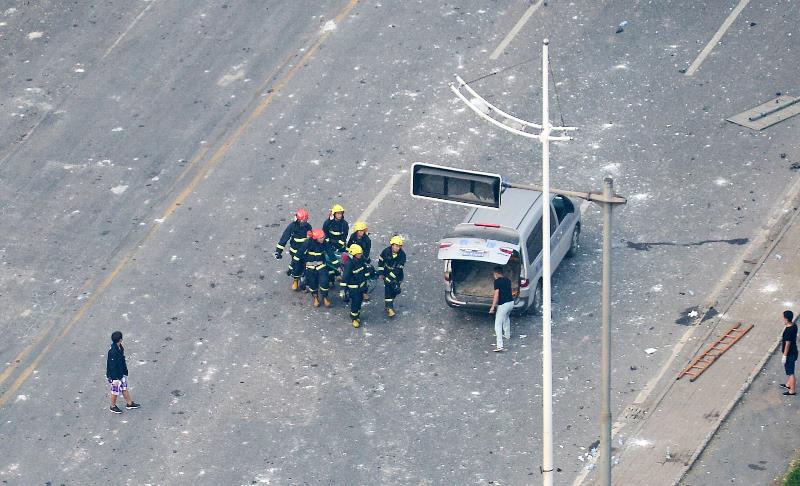 Rescuers carry a victim of the massive explosions onto a minivan in Tianjin on August 13, 2015.