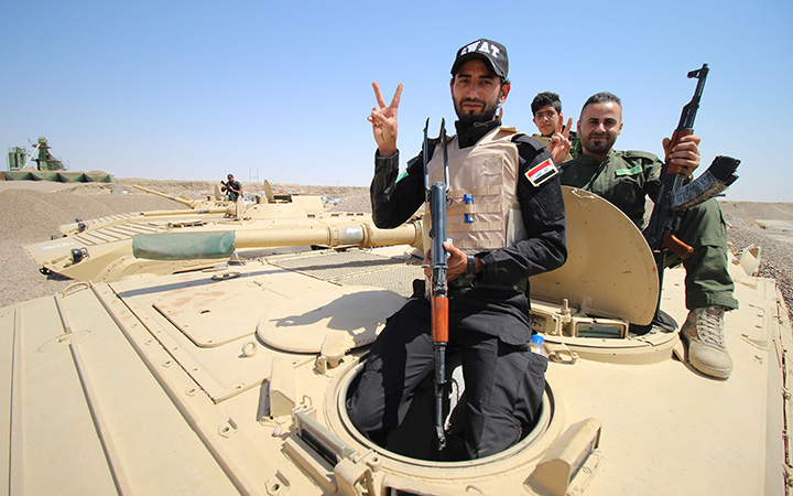 Members of the allied Iraqi forces consisting of the Iraqi army and fighters from the Popular Mobilisation units pose for a photo as they sit on a tank on the front line during a military operation against Islamic State (IS) group jihadists on the road leading to Saqlawiya, north of Fallujah, in Iraq's Anbar province on August 19, 2015. 