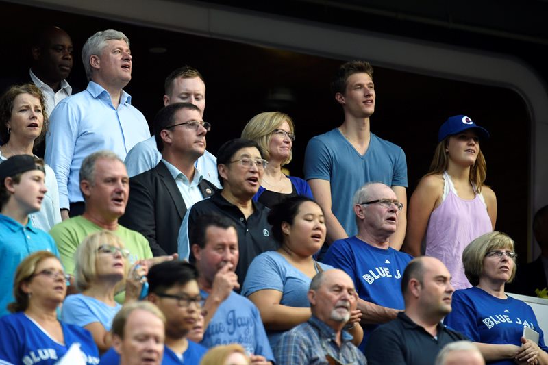 Conservative Leader Stephen Harper and his family sing the national anthem as the Toronto Blue Jays prepare to take on the Cleveland Indians during American League baseball action in Toronto on Monday, August 31, 2015.