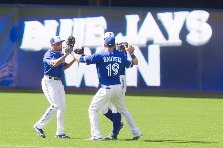 Toronto Blue Jays outfielders Jose Bautista (19) Ben Revere, left, and Kevin Pillar (obscured) come together in the outfield after defeating the New York Yankess 3-1 in their American League MLB baseball game in Toronto on Sunday, August 16, 2015.