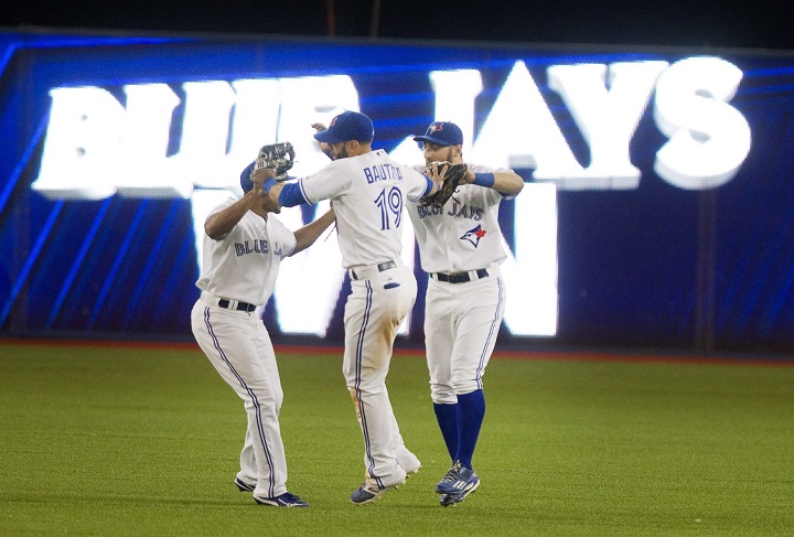 Toronto Blue Jays' Jose Bautista, Kevin Pillar and Ben Revere meet in the outfield after defeating the Oakland Athletics 10-3 in AL baseball action in Toronto on Wednesday August 12, 2015. THE CANADIAN PRESS/Fred Thornhill.