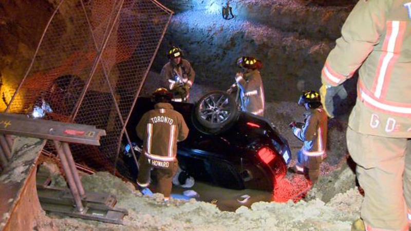 Firefighters work to pull the car out of a construction site on Aug. 22, 2015. 