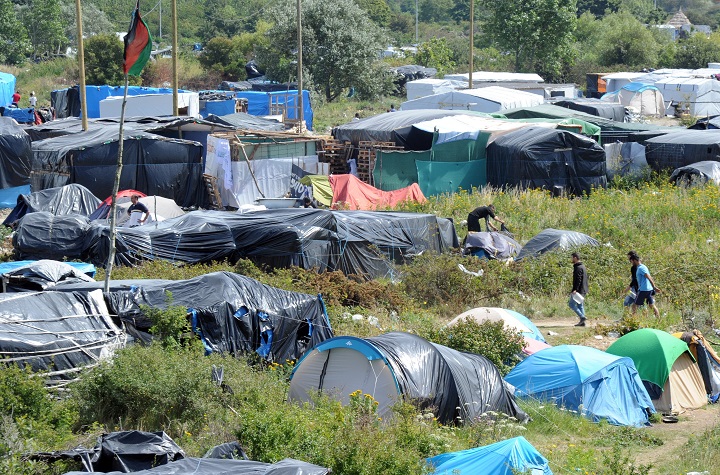People walk in the site dubbed "New Jungle", where migrants trying to cross the Channel to reach Britain have camped out, around the northern French port of Calais, on August 2, 2015.