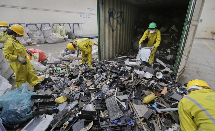 In this photo taken Monday, Aug. 18, 2014, workers unload and sort through a container full of electronic waste that was collected from a Nairobi slum and brought in for recycling, at the East African Compliant Recycling facility in Machakos, near Nairobi, in Kenya.